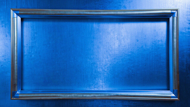 Metallic blue picture frame on textured wall, empty silver border for artwork, modern industrial background with copy space for presentation