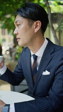 Japanese businessman drinking coffee at an outdoor cafe between meetings