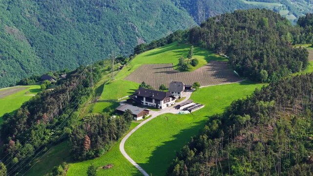 Mountain farm and cultivated fields in South Tyrol, Dolomites, Italy. Close aerial footage of farm buildings and green meadows in Alpine countryside to cattle farming