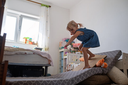  little girl balancing and jumping on mattress slide during active play at home