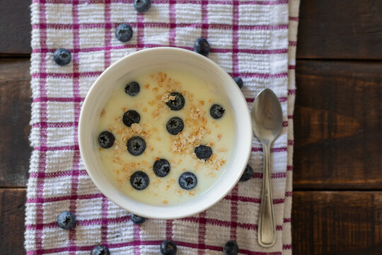 A healthy breakfast or snack: a bowl of yogurt with blueberries on a wooden table