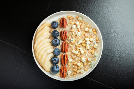 Oatmeal. Bowl of oatmeal porridge with blackberry, bananas and chia seeds on gray concrete old table background. Top view in flat lay style. Natural ingredients. Hot healthy breakfast and diet food