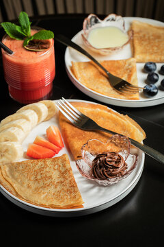 A plate of crepes filled with chocolate spread and topped with banana slices and mint