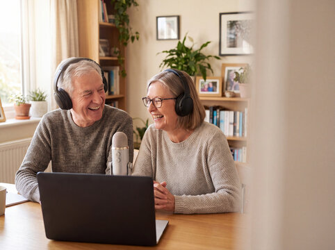 Cheerful Senior Couple with Headphones Recording Audio Podcast at Home