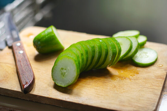 Sliced fresh green cucumber on a wooden cutting board with a kitchen knife, selective focus. cucumber on cutting board