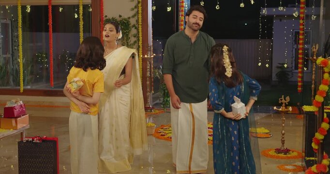 Indian happy male man woman standing with young adult female talk speak enjoy night diwali indoor place South family group child son boy girl kids give surprise gifts to parents spend quality time