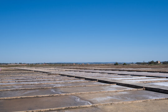 salt pans with evaporation ponds and wooden borders under clear blue sky