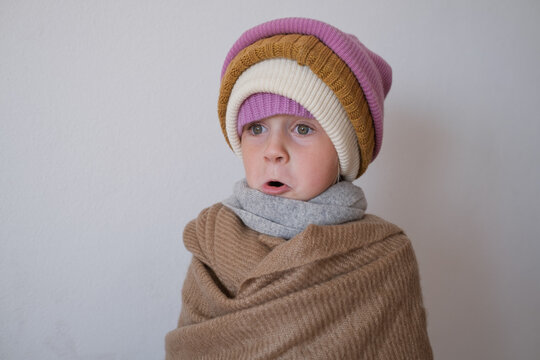  surprised little girl wearing multiple warm winter knitted beanies