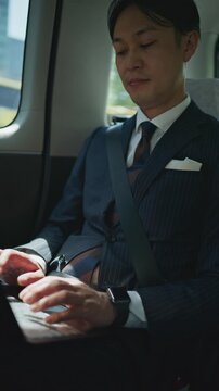 Businessman looking at his smartphone in a taxi with the seat belt fastened