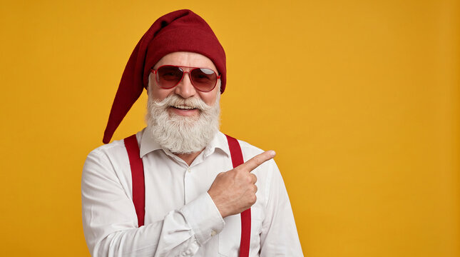Smiling senior businessman wearing santa hat pointing aside on yellow background perfect for corporate holiday sales and festive promotions