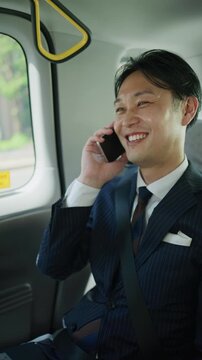 Businessman talking on the phone while riding in a taxi through the city