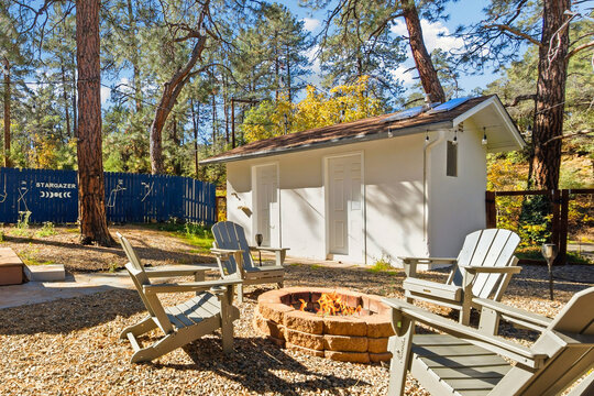 Outdoor fire pit seating near small white shed in forest