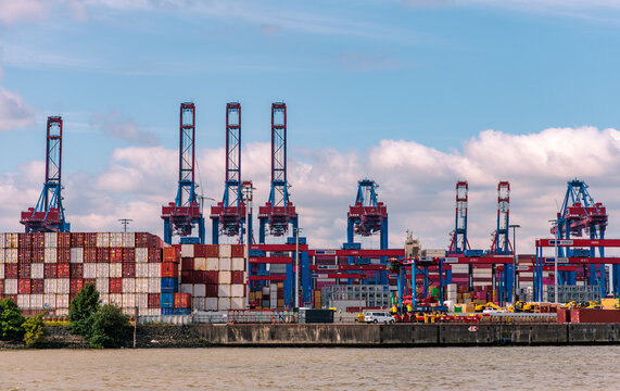 Port of Hamburg container terminal with tall gantry cranes and stacked shipping containers across water, international maritime shipping and logistics concept