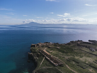 Aerial view of Isla de las Palonas, stone ruins and fortification walls on a overlooking calm blue sea and distant African mountains from Tarifa, Spain © Felix Morion