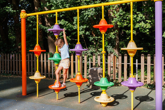 Happy Girl Playing on Colorful Playground Equipment in Sunny Park, Active Childhood and Outdoor Fun