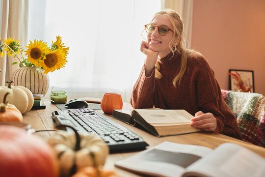 Smiling woman studying in a cozy home office.