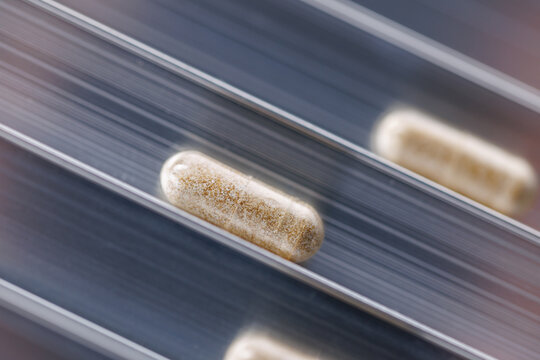 Closeup capsule with natural herbs production line background with motion blur and diagonal capsules for pharmaceutical