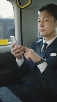 Japanese businessman using a smartphone in the back seat of a taxi