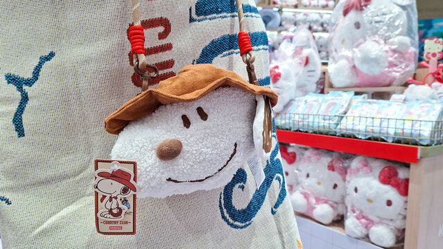 cute snoopy plush crossbody shoulder bag wearing brown hat hanging on display on September 16, 2026 in Bangkok, Thailand.