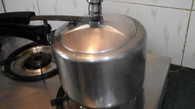 Pressure cooker on a gas stove releasing steam through the pressure regulator