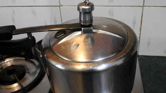 Cooking dal or boiling potatoes in a pressure cooker at indian kitchen