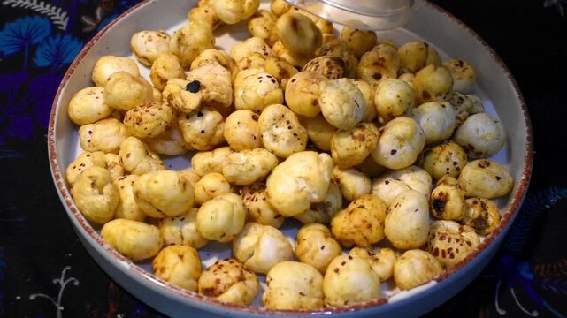 pouring flavored roasted makhana from a box onto a plate