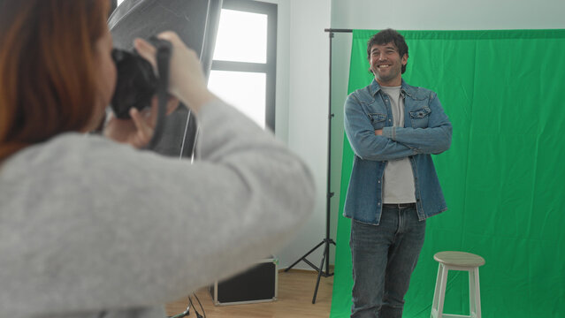 Man and woman photographers inspect dslr camera as woman gestures with hand and holds strap in studio; teaching collaboration.