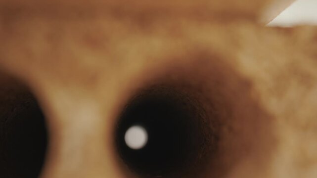 Macro pull out shot through tubular hole of stacked wood particle board panels showing perforated hollow core chipboard texture