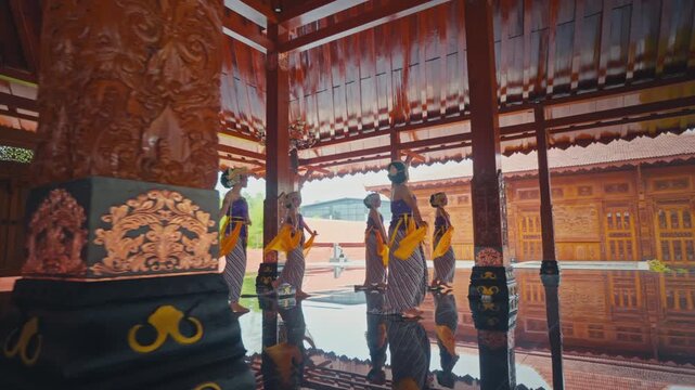 Traditional Dancers Walking in Line on Reflective Floor in Pendopo