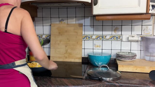 Mujer cocinando huevos revueltos en cocina mediterr&aacute;nea