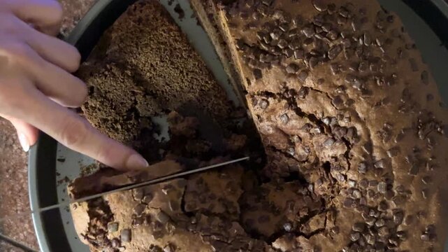 Mano cortando bizcocho de chocolate desde cenital