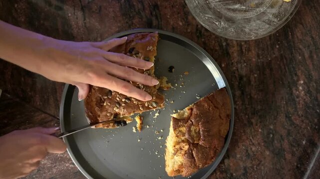 Manos cortando bizcocho de semillas desde cenital
