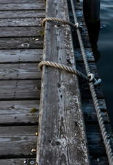 Fototapeta premium Travel and adventure concept, weathered wooden pier with nautical rope mooring at a lake dock for maritime transportation and summer vacation leisure