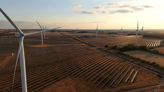 Hybrid solar farm and wind turbines at golden hour sunset in an aerial view in Chelveston, UK