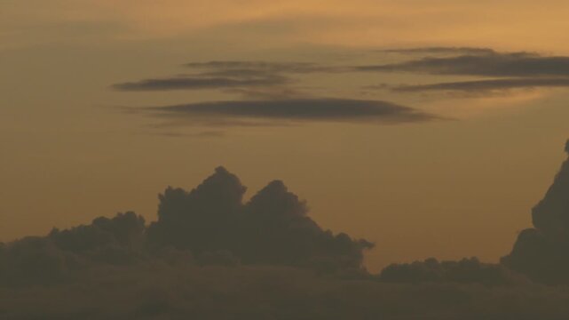 Silhouetted Clouds Against Bold Orange Sunset Gradient Sky