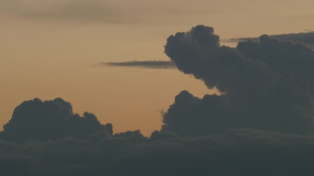 Silhouetted Clouds Against Bold Orange Sunset Gradient Sky