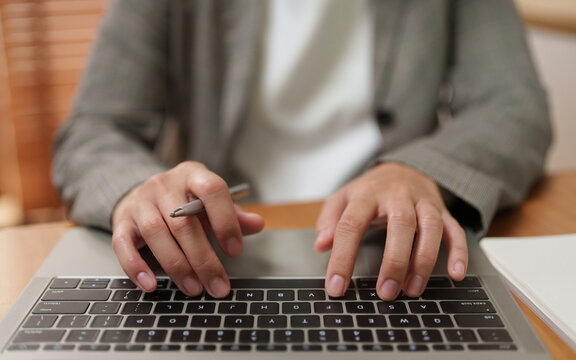 Businesswoman typing on a laptop while working at an office desk, representing online browsing, professional work, business productivity, digital technology and modern workplace tasks.