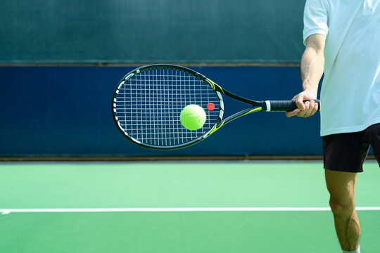 Tennis Player Hitting Ball with Racket on Blue and Green Hard Court Close Up Action Shot
