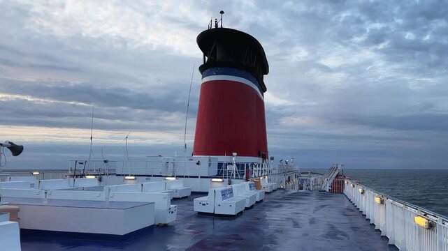 Cruiseferry upper deck with smokestack against sea at overcast morning