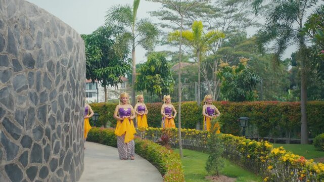 Line of Traditional Dancers Walking Along Curved Garden Path