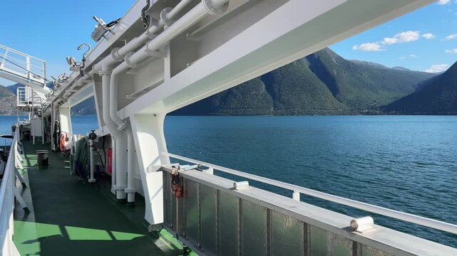 Lateral structures on moving car ferry deck against fjord coastland