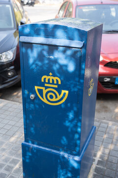 Sabadell, Spain - August 14th 2026 - Blue Spanish postbox with yellow postal logo named Correos on the street
