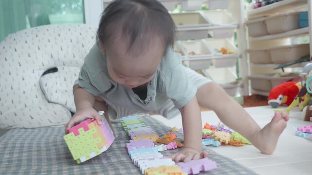 A toddler engrossed in play, carefully assembling colorful building blocks on the floor. The bright colors and creative play encourage cognitive development and fine motor skills.