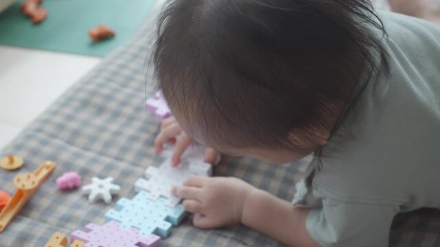 A toddler enthusiastically explores colorful puzzle pieces on a play mat, developing fine motor skills and creativity. The vibrant shapes and textures invite imaginative play, fostering cognitive deve