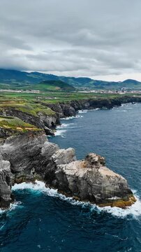 Volcanic headland forms bold section of Sao Miguel coastline in Azores, Portugal. High rocky cliffs stand above open Atlantic Ocean