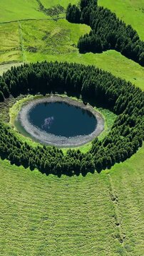 Lake inside volcanic crater with green forest ring, Sao Miguel Island, Azores, drone footage