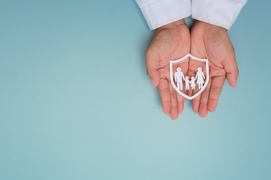 Doctor hand holding family health insurance shield paper cutout with protective care offering safe secure life coverage support