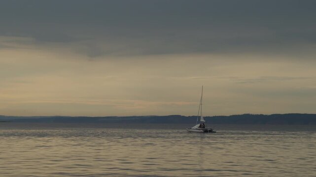 Sailing boat moves on the lake with during sunset