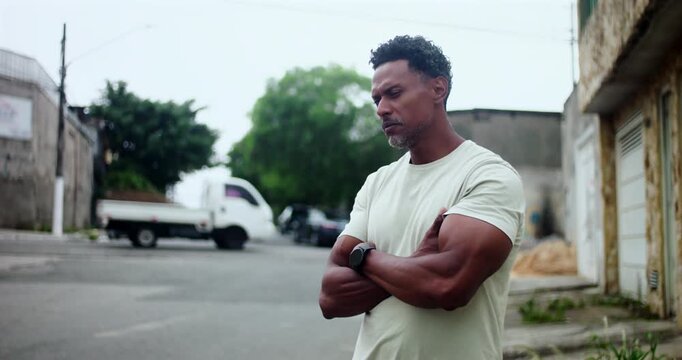 Hispanic Afro-Latin man angrily discussing with someone off camera, expressive gestures, arms crossed, intense conversation, urban street setting, argument, frustration