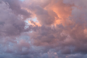 Fototapeta premium Close-up of a fluffy sunset orange clouds on the blue sky.